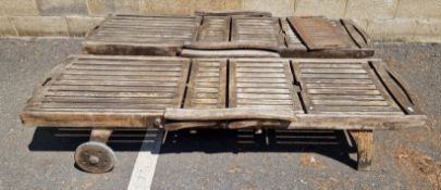 A pair of weathered two-wheeled teak garden loungers, 203cm L x 63cm wide, excl. wheels