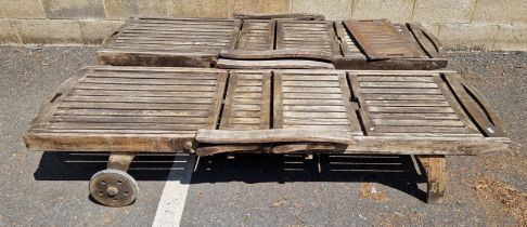 A pair of weathered two-wheeled teak garden loungers, 203cm L x 63cm wide, excl. wheels