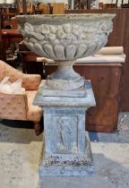 A large bowl-shaped reconstituted stone garden urn on a square stepped base, the bowl semi-gadrooned