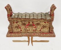 Indonesian wooden gamelan metallophone, the bronze chimes on a carved red lacquered base with gilt