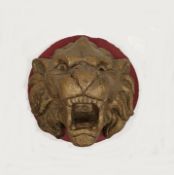 Composite stone circular relief plaque depicting a roaring lion's mask, painted red and gold, 22cm