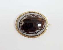 19th century gold-coloured metal, brown and white banded agate brooch, oval with engraved border,