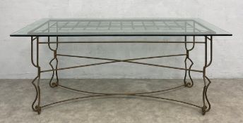 A vintage dining table with bevelled plate glass top raised on a shaped and stretchered wrought iron