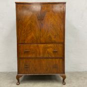 A mid century Art Deco walnut tallboy with a pair of figured cupboard doors enclosing two shelves