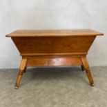 A 19th century pine dough box table with plank top over the tapered trough raised on turned