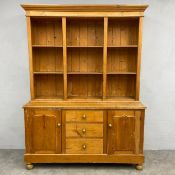 A C.1900 pine dresser in two parts with three shelves over base cabinets and drawers raised on bun