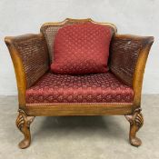 An early 20th century walnut bergere armchair with shaped cane back and arms over the needlework