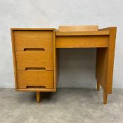A mid-century oak dressing table with black laminate top enclosing mirror and compartment over three