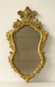 A 19th century carved giltwood wall mirror with original shaped plate in a scrolling Baroque style