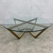 A contemporary coffee table with plate glass top on angular brass base. H.35 Diam.106cm.