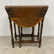 An early 20th century oak drop-leaf table with carved oval top raised on turned and stretchered