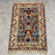 A Caucasian Kazak rug with stylised flowerhead and figural field over a duck egg ground within