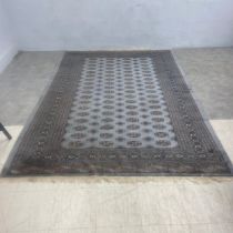 A Bokhara carpet with repeated gul motifs on a powder blue ground within multiple stylised