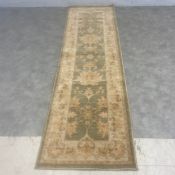 A Persian style Zeigler runner with scrolling foliate field over a sage ground within a stylised