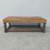 A small 19th century Spanish style footstool with tan leather stuffover studwork top raised on