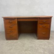 A mid-century teak twin pedestal desk with frieze drawer and brushing slides over eight drawers