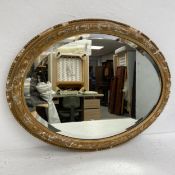 A 19th century wall mirror with oval bevelled plate in a gilt gesso frame. 65x50cm.