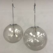 A pair of mid-century globe pendant ceiling lamps with spherical blown glass shades and chrome
