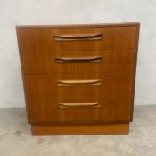 A mid-century teak chest of four graduating drawers with scrolled handles raised on a square