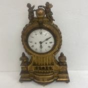 An 18th or 19th century French carved giltwood mantle clock with figural putti cresting over the