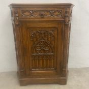 An early 20th century Gothic Revival oak side cabinet with shaped top over the carved frieze