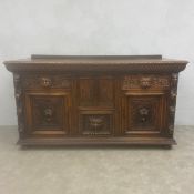 An early 20th century Renaissance Revival oak sideboard having a plank top with carved frieze over