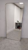 A large contemporary wall hanging mirror with shaped plate in a brass slip frame. H.200 W.90cm (with