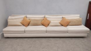 A large contemporary four seater sofa with square back and striped cotton upholstered seat raised on