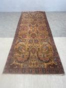 A Persian Kerman carpet runner with allover polychrome foliate field over a mustard abrash ground
