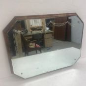 A vintage octagonal wall mirror with bevelled and garland engraved plate on a crossbanded mahogany