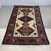 A Caucasian Kazakh style carpet with stepped pole medallion in a polychrome field over a beige