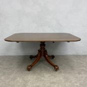 A Regency mahogany dining table with tilt-top action on pedestal base with swept quadruped