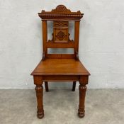 A late 19th century walnut hall chair with shaped and carved back-rail above panel seat raised on