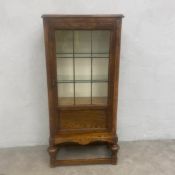 A mid 20th century oak display cabinet with thumb moulded top over the leaded glazed door