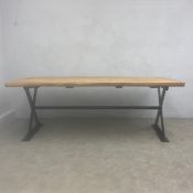 A vintage refectory or farmhouse style dining table with thick plank top raised on a stretchered