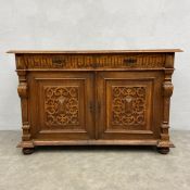 A 19th century Continental oak sideboard with frieze drawers above panel doors flanked by carved
