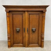 A 19th century oak cabinet with panel doors and lion mask handles flanked by turned pilasters. H.