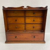 A C.1900 mahogany tabletop apprentice chest of seven drawers with shaped gallery back raised on a
