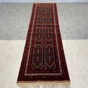 A Persian Baluch runner with two rows of three diamond lozenge medallions in a polychrome field over