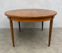 A mid-century teak G-Plan extending ding table having a circular top with integrated bi-fold leaf
