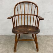 A 19th century oak Windsor armchair with stick back and arms over the shaped saddle seat raised on