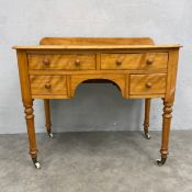 A 19th century satin birch side table or kneehole desk with an arrangement of drawers on turned