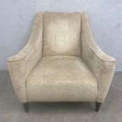 A contemporary lounge armchair with square back and swept arms over the beige chenille upholstered