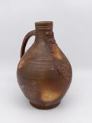 A 17th century salt-glazed terracotta Bellarmine or Bartmann jug with bearded face mask, incised