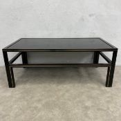 A vintage black painted metal coffee table with a square black glass inset top raised on straight