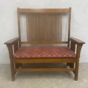 An Arts & Crafts style oak 'Mission' hall bench with straight stick back and needlework