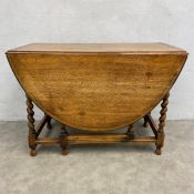 A 19th century oak drop leaf dining table with thumb-moulded oval top raised on stretchered barley-