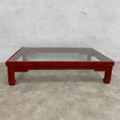 A small Chinese red lacquered low table with drop in plate glass top. H.16 W.65 D.44cm.