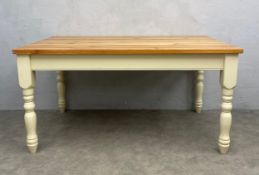 A contemporary pine farmhouse style dining table with plank top raised on turned and painted