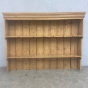 A C.1900 pine dresser plate rack with moulded cornice over two shelves with shaped waterfall end-
